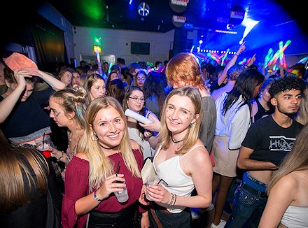 Two ladies smiling at a glow pary